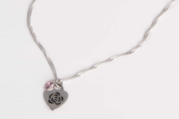 Collar con cadena de plata y medalla en forma de corazón .Tiene un grabado láser de una flor y una circonita colgate rosa
